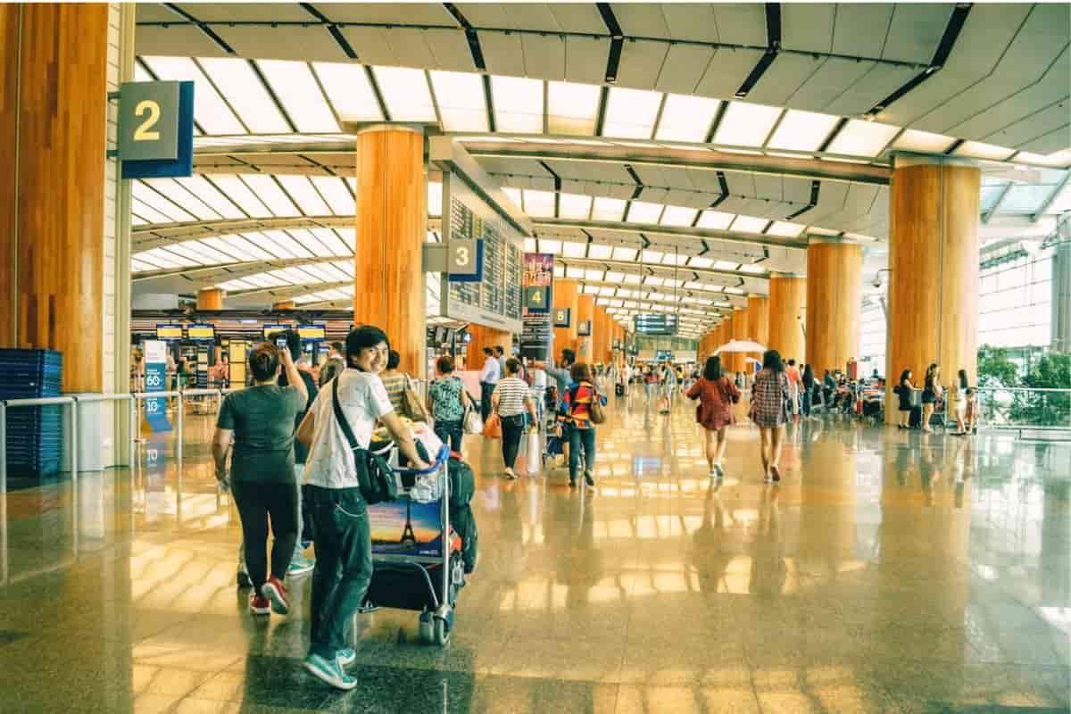 traveling passenger pushing airport trolley happily